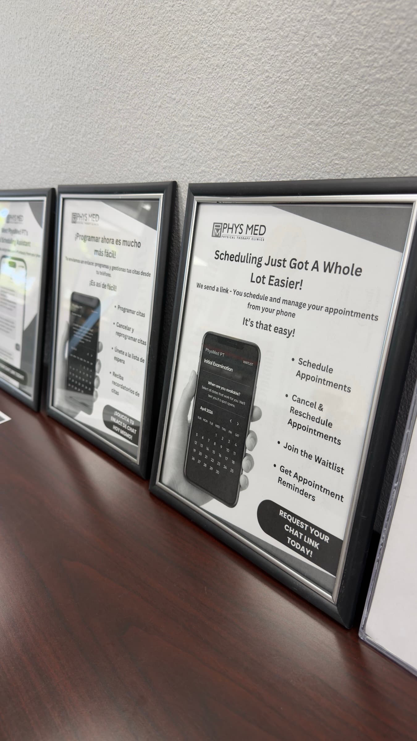 English and Spanish 'Scheduling Just Got a Whole Lot Easier' posters at the Phys Med front desk